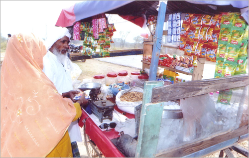Hassan selling wares to a woman in his mobile shop